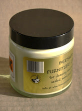Load image into Gallery viewer, Jar of beeswax furniture cream with a black lid on a gold background